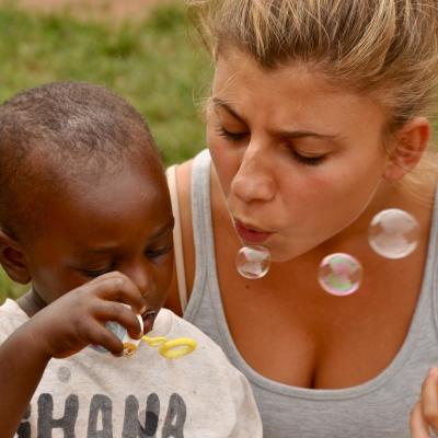 A Projects Abroad volunteer plays with a child during her Childcare Project in Ghana Childcare volunteer blows bubbles with a child in Ghana
